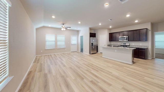 kitchen featuring stainless steel appliances, recessed lighting, open floor plan, a sink, and dark brown cabinets