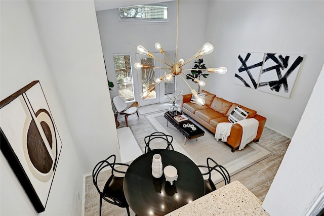 living area with a high ceiling, wood finished floors, and an inviting chandelier