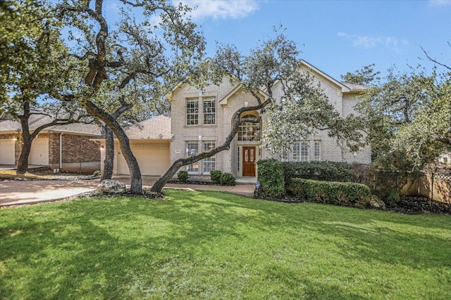 traditional-style house featuring driveway, brick siding, an attached garage, and a front yard