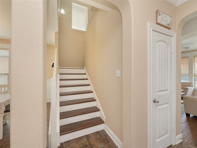 stairs with baseboards and arched walkways