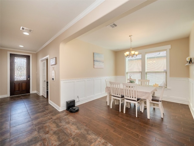 dining room with visible vents, wainscoting, dark wood-style floors, ornamental molding, and a notable chandelier