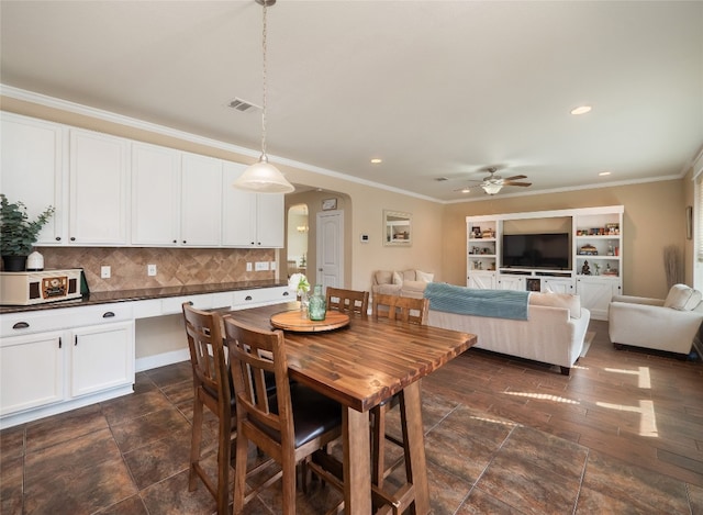 dining area featuring a ceiling fan, visible vents, arched walkways, and crown molding