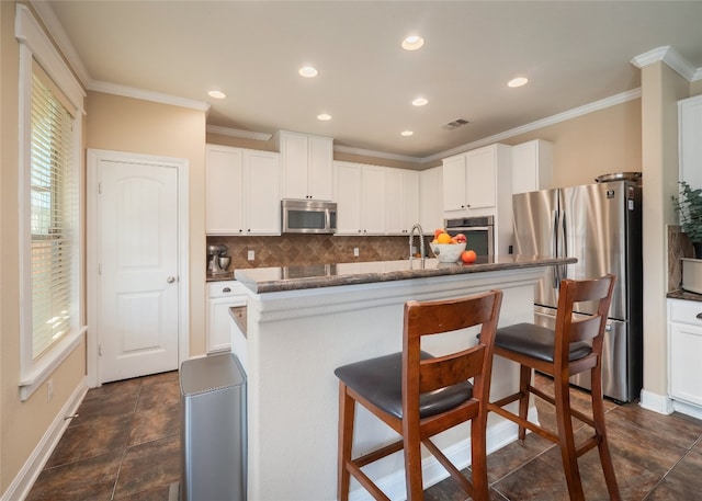 kitchen featuring stainless steel appliances, a breakfast bar, a healthy amount of sunlight, and visible vents