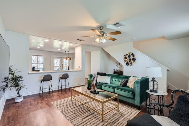 living room featuring stairway, baseboards, visible vents, and wood finished floors