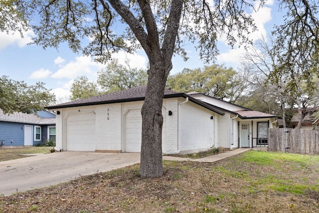 exterior space featuring a garage, concrete driveway, brick siding, and fence