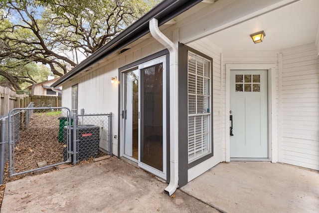 entrance to property with cooling unit, a gate, and fence