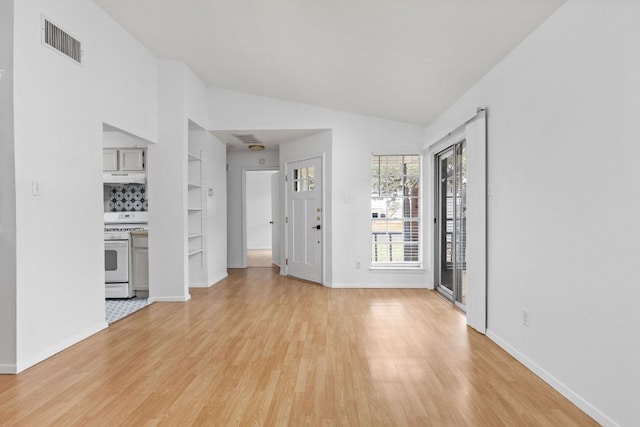 interior space featuring lofted ceiling, light wood finished floors, visible vents, and baseboards