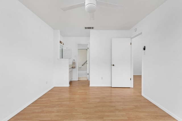 unfurnished bedroom featuring light wood finished floors, baseboards, visible vents, a ceiling fan, and ensuite bath