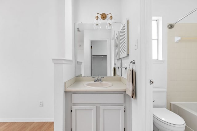 bathroom with baseboards, toilet, wood finished floors, tub / shower combination, and vanity