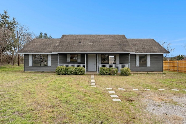 view of front facade featuring covered porch, a shingled roof, fence, and a front yard