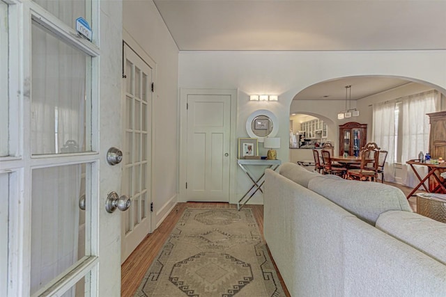 foyer entrance with arched walkways and light wood finished floors