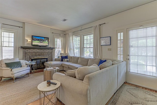 living room featuring light wood finished floors, a fireplace, and visible vents