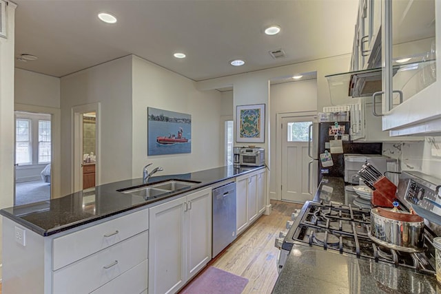 kitchen with recessed lighting, appliances with stainless steel finishes, white cabinets, a sink, and light wood-type flooring