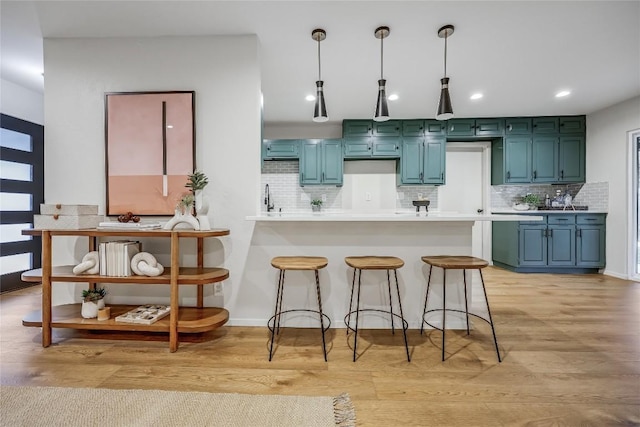 kitchen with a peninsula, tasteful backsplash, a breakfast bar area, and light wood-style floors