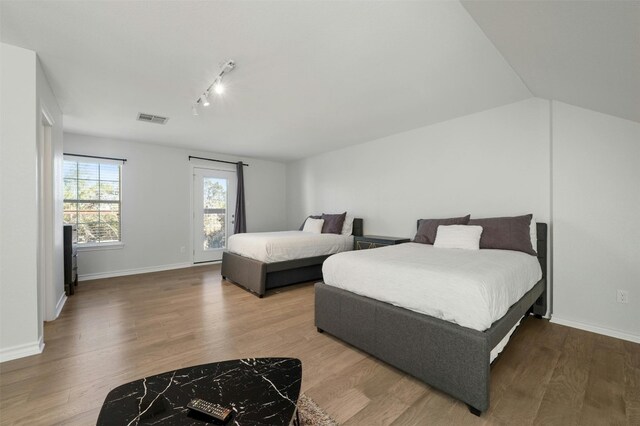 9288 Scenic Bluff Dr, Austin, TX 78733 - bedroom featuring rail lighting, wood finished floors, and baseboards