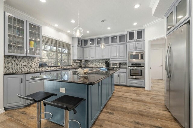 9288 Scenic Bluff Dr, Austin, TX 78733 - kitchen with appliances with stainless steel finishes, gray cabinetry, decorative backsplash, crown molding, and recessed lighting