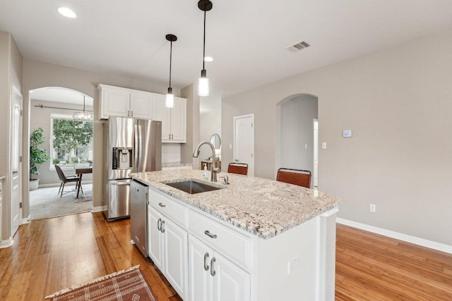 kitchen featuring white cabinetry, arched walkways, stainless steel appliances, and a sink