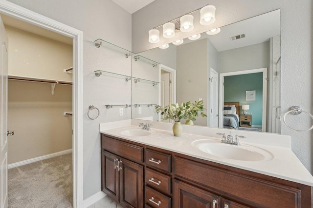 bathroom with connected bathroom, visible vents, a sink, and double vanity