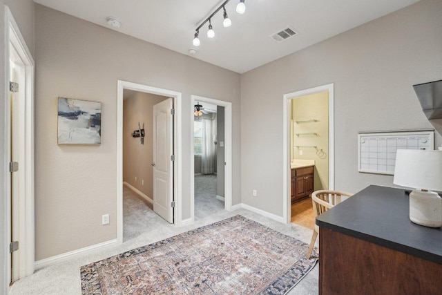 home office featuring rail lighting, baseboards, visible vents, and light colored carpet