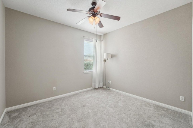 carpeted empty room featuring ceiling fan and baseboards