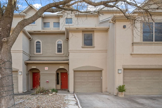 multi unit property featuring a garage, driveway, and stucco siding