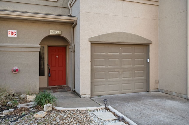 view of exterior entry with a garage and stucco siding