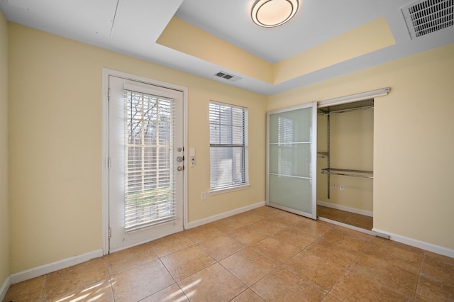 entryway with plenty of natural light, visible vents, a raised ceiling, and baseboards