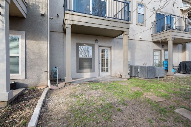 entrance to property featuring central AC, a balcony, and stucco siding