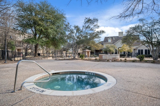 view of swimming pool with fence and a hot tub