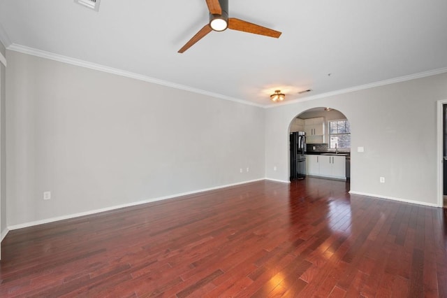 unfurnished living room with dark wood-style floors, arched walkways, ornamental molding, and baseboards