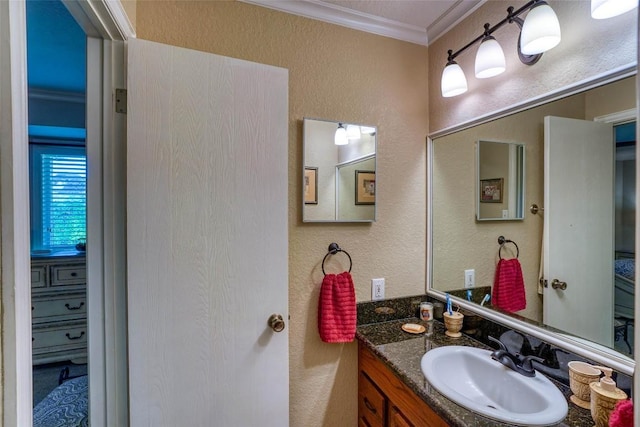 bathroom featuring vanity, crown molding, and a textured wall