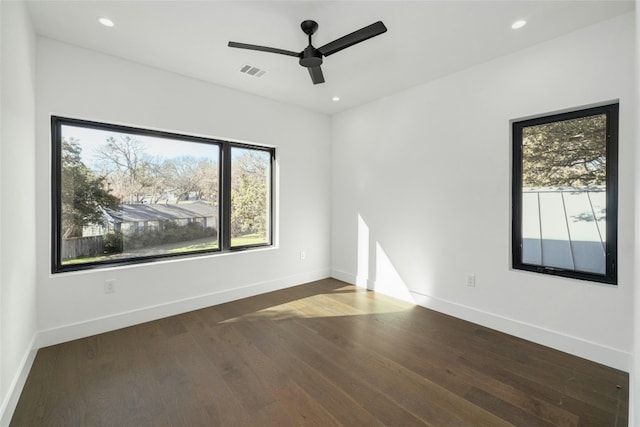 spare room with dark wood-style floors, visible vents, and baseboards