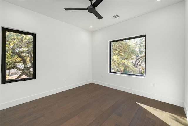 unfurnished room with dark wood-style floors, a wealth of natural light, visible vents, and baseboards