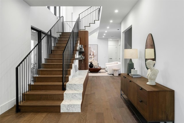 stairway with baseboards, hardwood / wood-style floors, a high ceiling, and recessed lighting