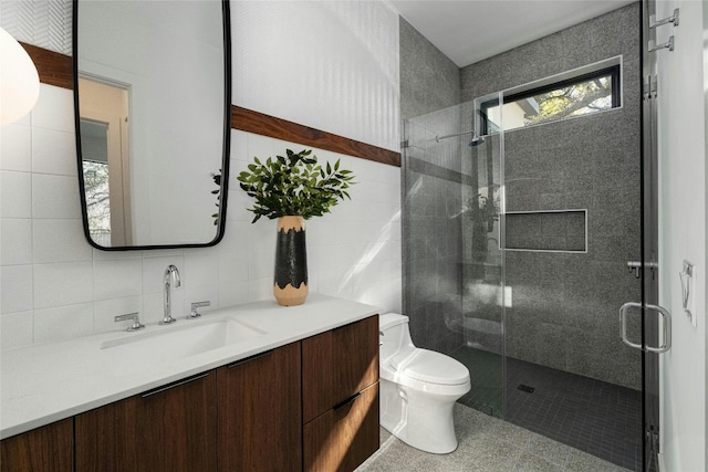 bathroom with tile walls, a shower stall, toilet, and vanity