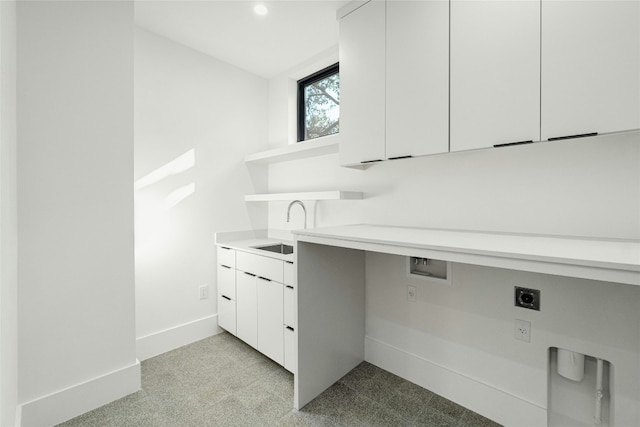 clothes washing area featuring light colored carpet, cabinet space, hookup for an electric dryer, a sink, and baseboards