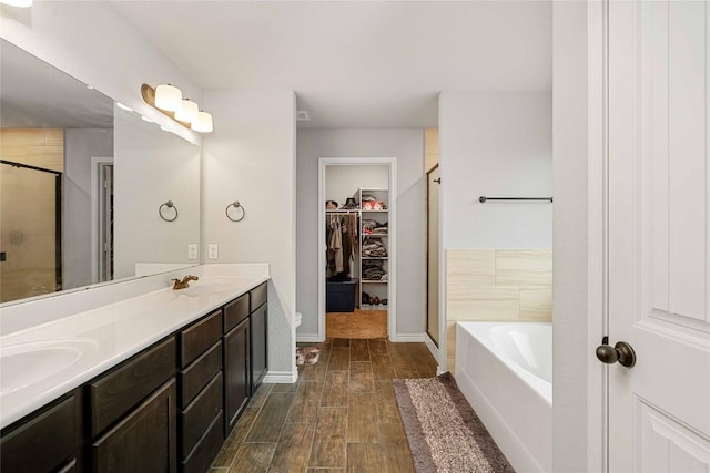 903 Mclaury Cv, Killeen, TX 76542 - bathroom featuring a stall shower, a bath, wood finished floors, a spacious closet, and double vanity