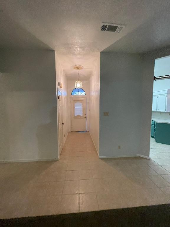 entryway featuring light tile patterned floors, baseboards, visible vents, and a textured ceiling