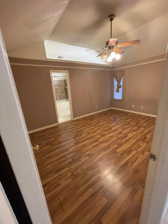 spare room with ceiling fan, vaulted ceiling, wood finished floors, and baseboards