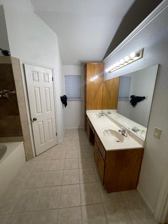 full bath with lofted ceiling, a sink, a bath, and tile patterned floors