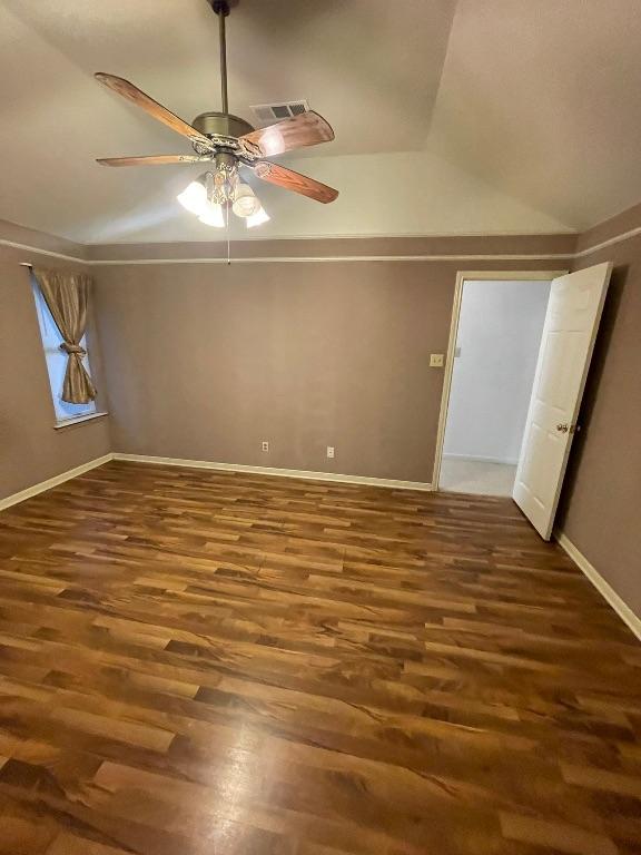 empty room with lofted ceiling, wood finished floors, visible vents, and a ceiling fan