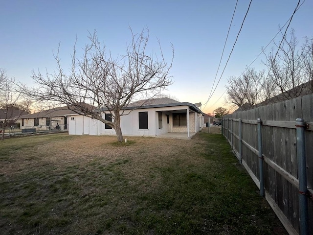 back of property with a yard, a patio area, and a fenced backyard