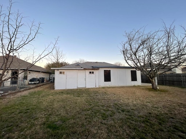 back of property featuring a yard, board and batten siding, and fence