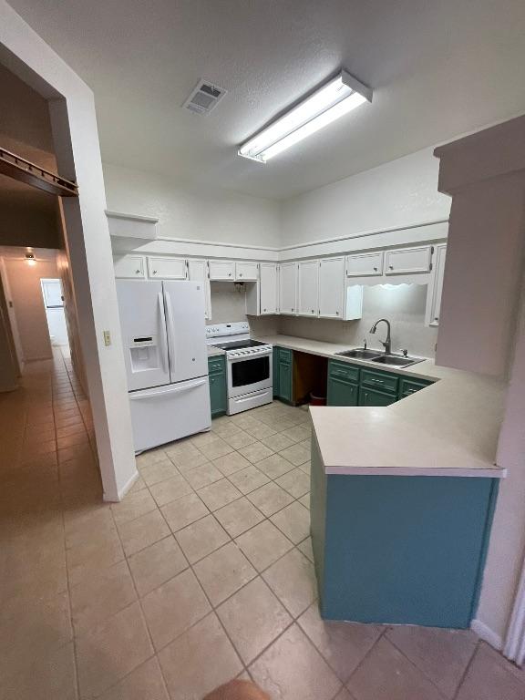 kitchen featuring a peninsula, white appliances, a sink, visible vents, and light countertops