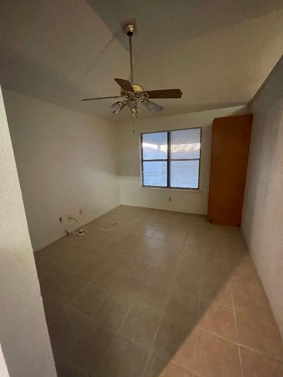 empty room featuring lofted ceiling, light tile patterned floors, and ceiling fan