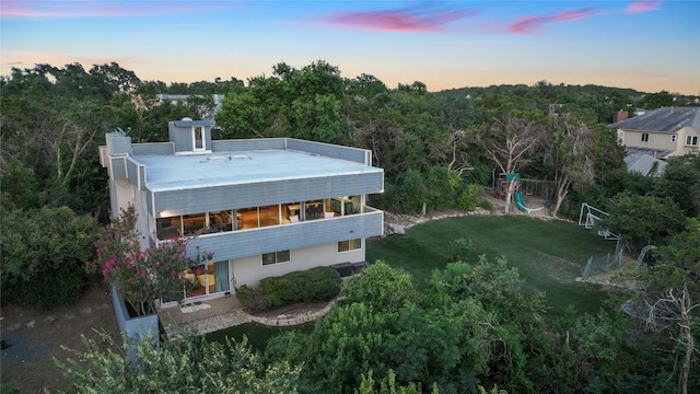 back of property at dusk with a lawn