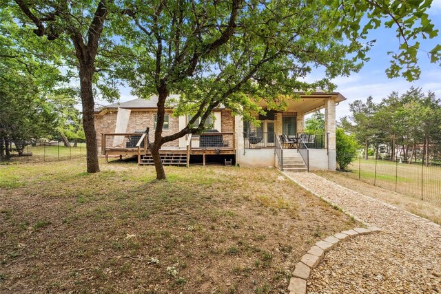 back of house featuring fence, covered porch, and a yard