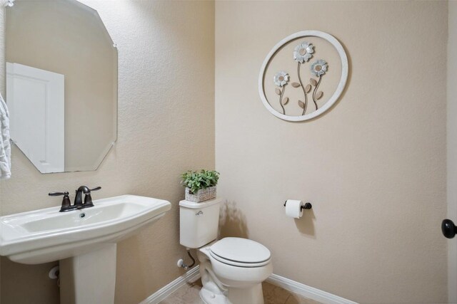 bathroom with baseboards, a sink, tile patterned flooring, and toilet