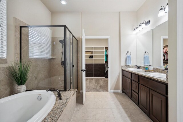 bathroom with double vanity, a sink, a bath, and a stall shower