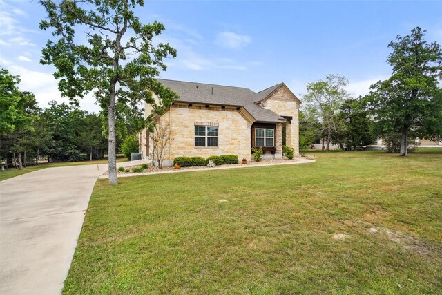 french provincial home with stone siding, a front lawn, and concrete driveway